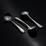 Three silver cupping spoons on a black background